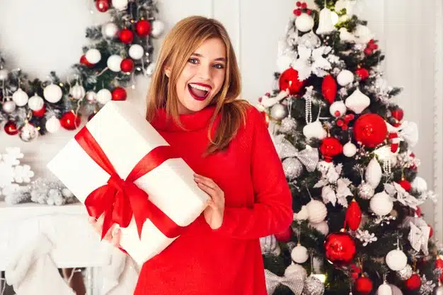 Smiling woman with many gift boxes posing near decorated christmas tree Free Photo