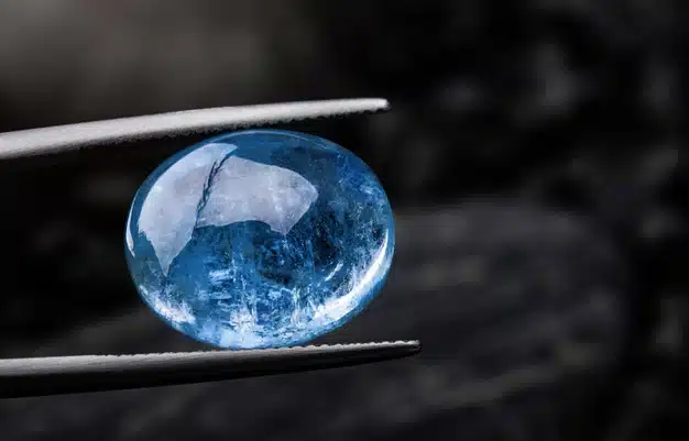 Indigo blue sapphire gemstone with dark rock background. Premium Photo