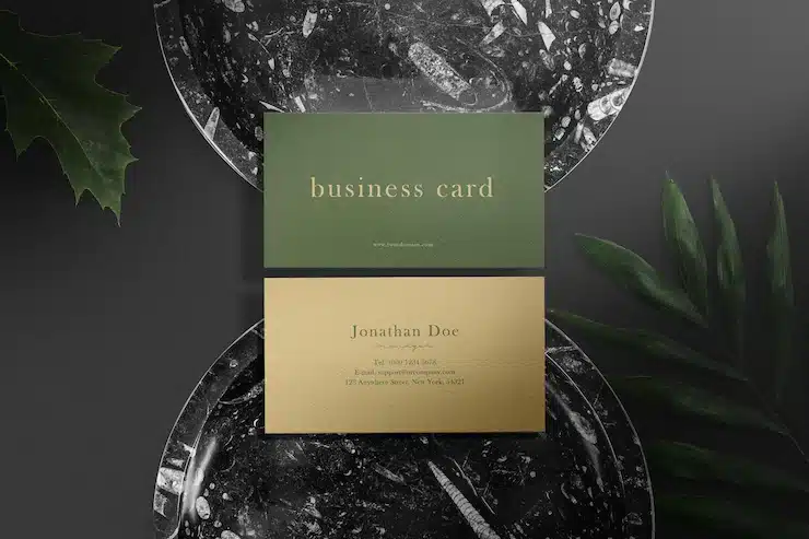 Clean minimal business card mockup on black marble plate with leaves